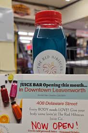 Bottle of juice with a flyer announcing The Red Hibiscus Juice Bar opening.