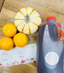 Jug of cider with oranges and a small pumpkin from The Red Hibiscus Juice Co.
